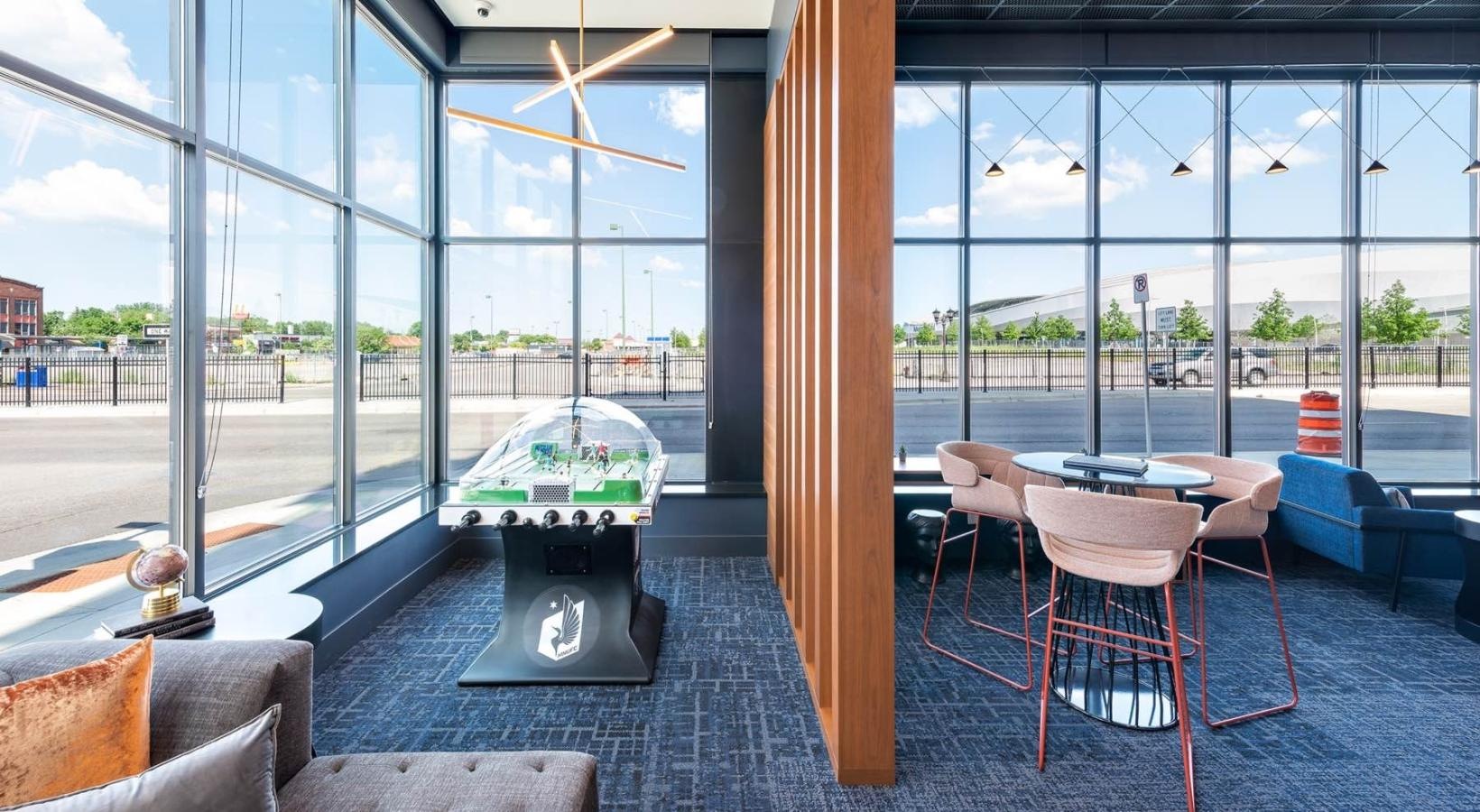 Take advantage of all Pivot has to offer a room with a table chairs and a large window with a view of the city